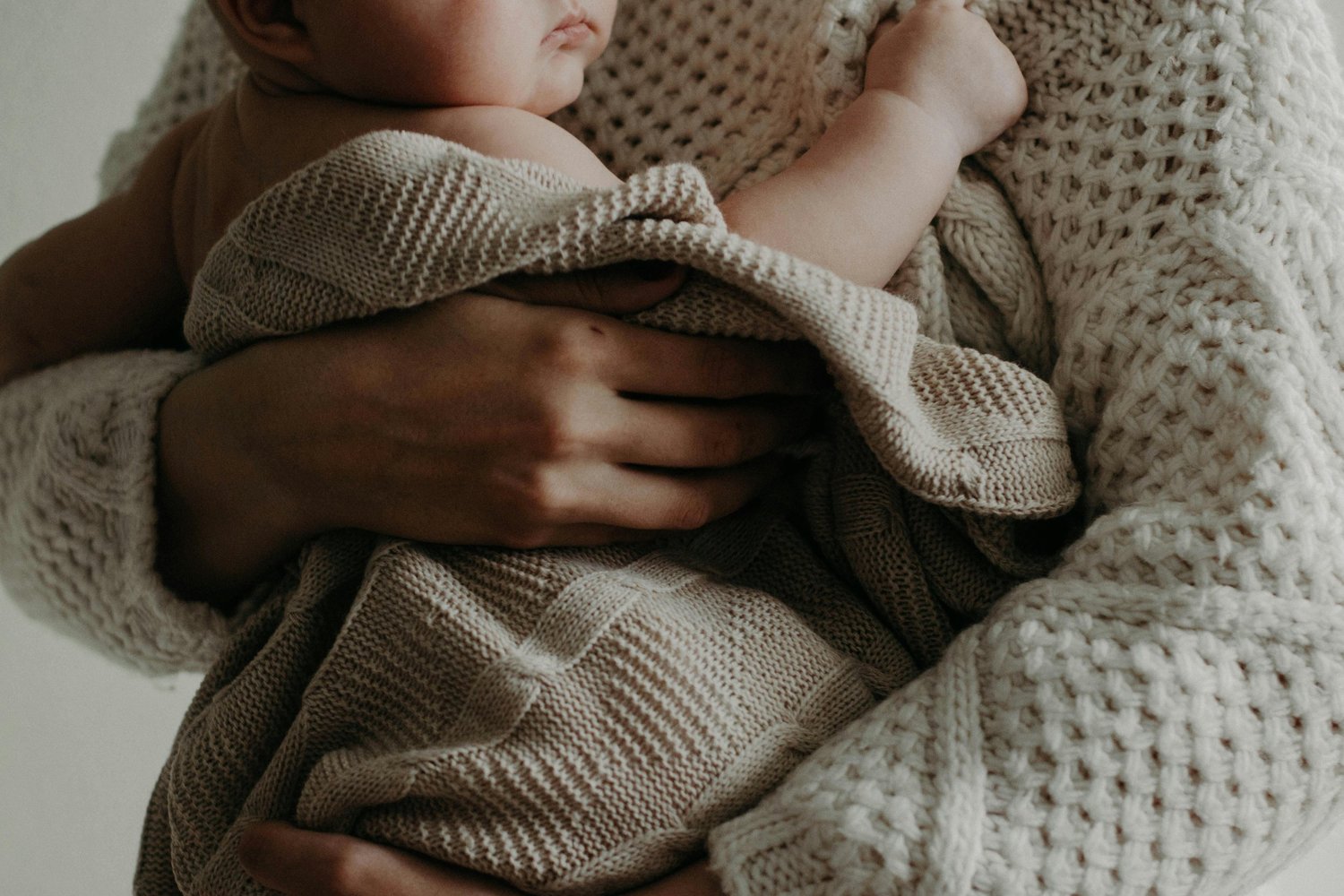 A newborn nestled in a parent’s arms