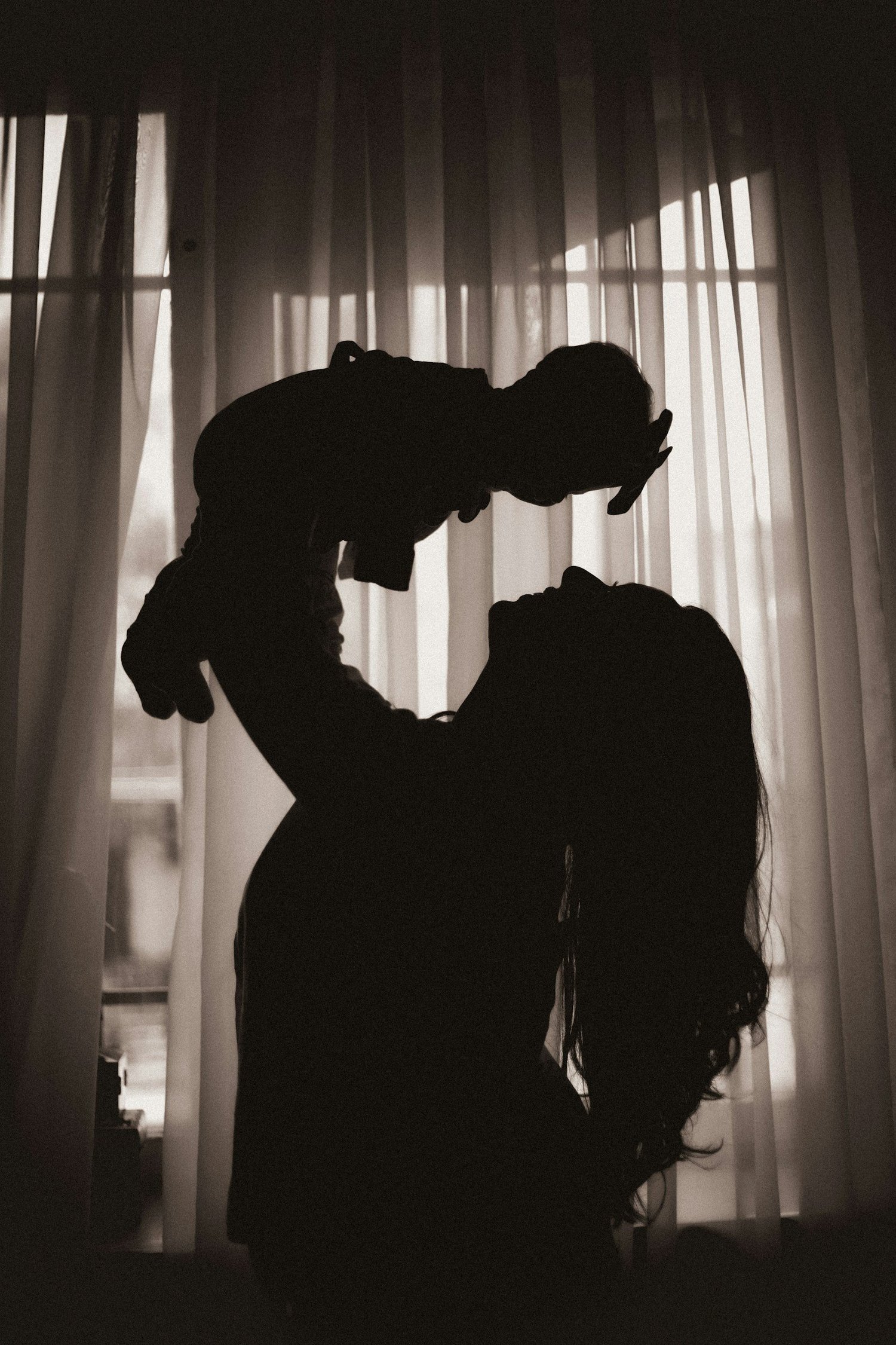 A mother lifting her baby toward the light